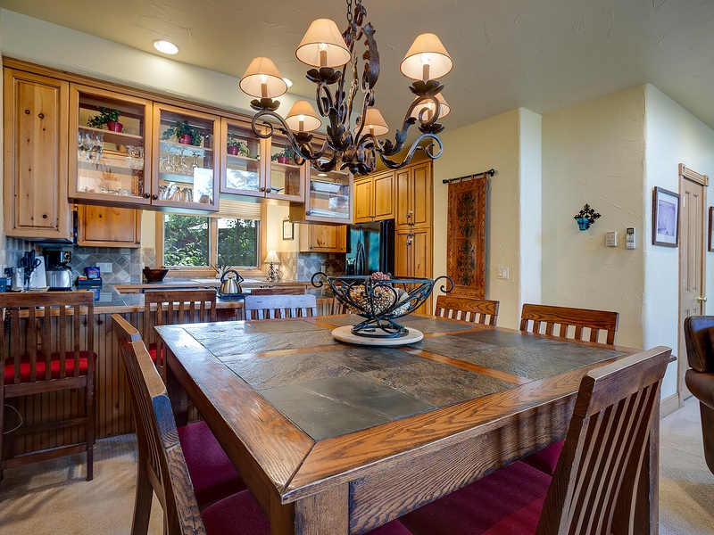 Gather around this handsome dining table under a stunning wrought-iron chandelier. The adjoining open kitchen invites you to whip up meals while staying connected with your group.