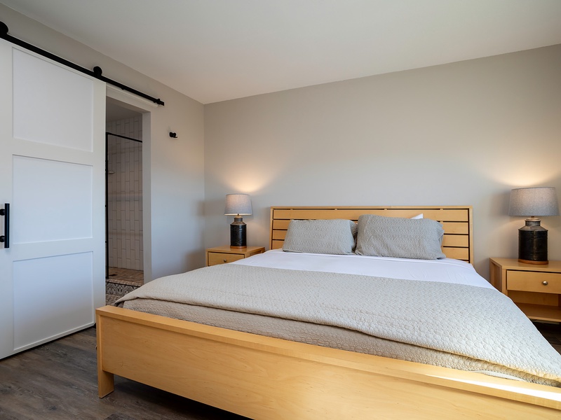 Sink into crisp white linens and warm wood tones in your serene bedroom. The charming barn door opens to your private ensuite, where every detail is designed for your comfort and relaxation.