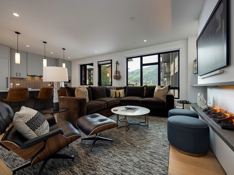 Sink into plush seating in your open-concept living space, where a warm fireplace and mountain vistas through expansive windows create the perfect backdrop for cozy evenings and memorable conversations.
