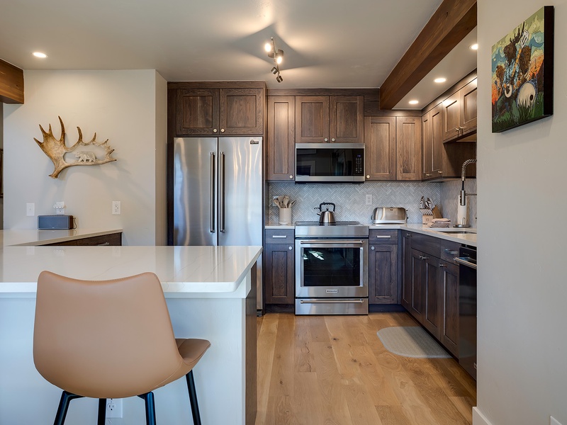 Your beautifully appointed kitchen features custom cabinetry, stainless appliances, and a sleek breakfast bar—perfect for whipping up morning coffee or evening meals.