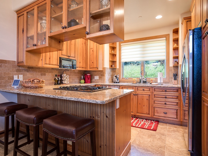 You'll love cooking in this warm, beautifully appointed kitchen featuring rustic pine cabinetry, granite countertops, stainless appliances, and plenty of natural light pouring in.