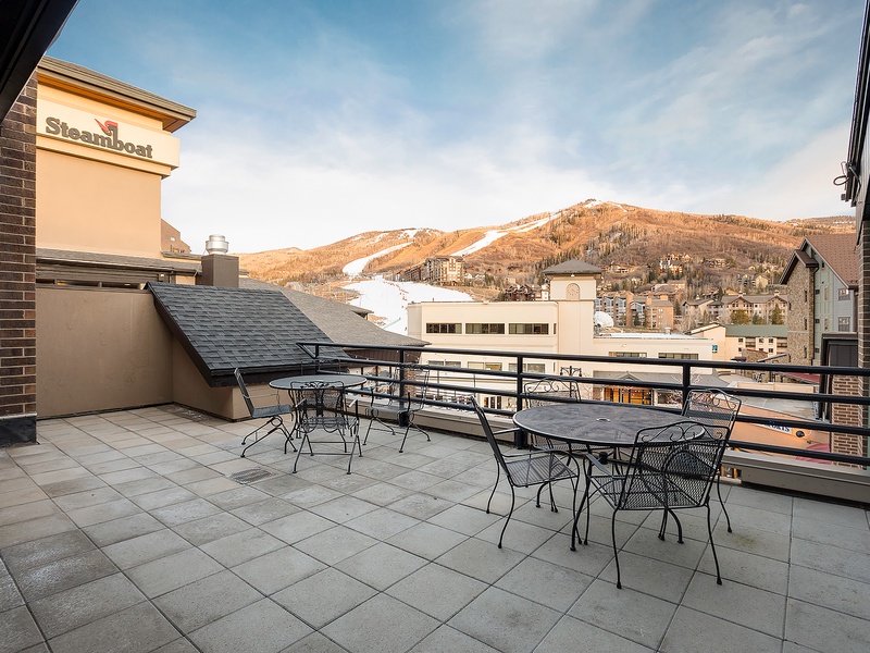 Rooftop terrace offers outdoor seating with mountain views, adjacent to a Steamboat-branded building in a ski resort setting.