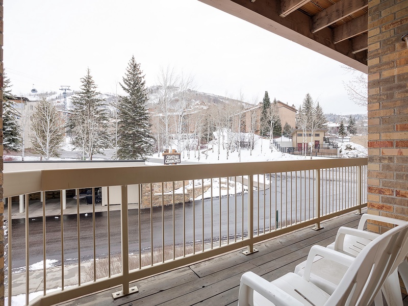 A snow-dusted ski village nestles among evergreens and mountain slopes, framed by a private balcony where winter adventure begins just steps away.