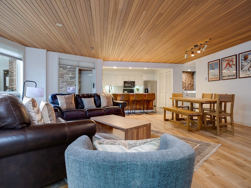 Relax beneath stunning wood ceilings in your spacious open-plan living area, where cozy seating, a full kitchen, and a welcoming dining table invite you to unwind after your adventures.