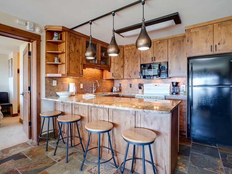 Your fully equipped kitchen features warm wood cabinetry, granite countertops, and a welcoming breakfast bar perfect for morning coffee or casual meals with loved ones.