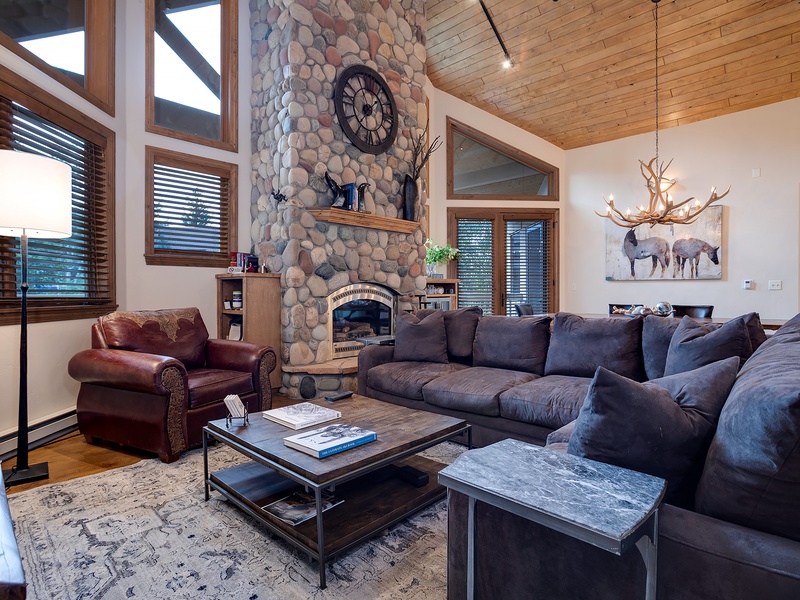 Sink into plush seating by your own stone fireplace, where rustic charm meets cozy mountain elegance under soaring wood ceilings.