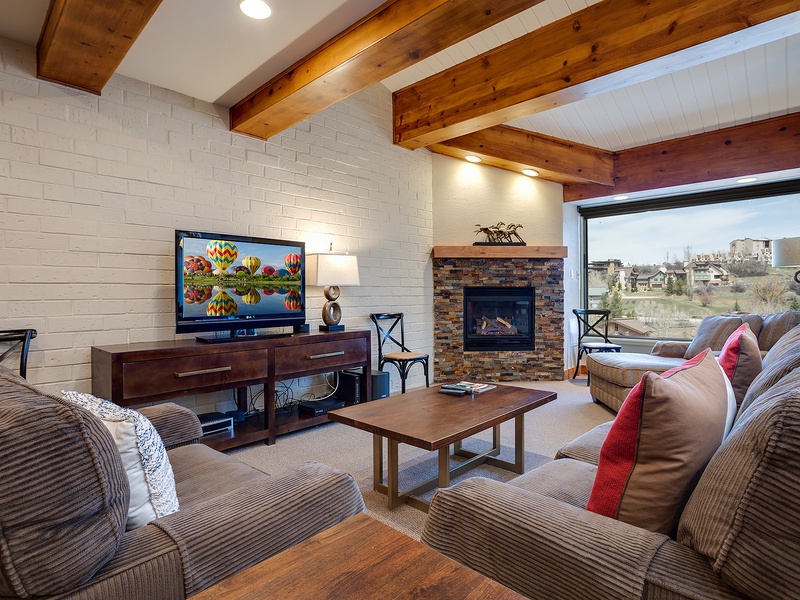 Unwind in your inviting living space, where exposed wood beams frame plush sofas, a cozy fireplace, and sweeping views that make every moment feel like a true getaway.