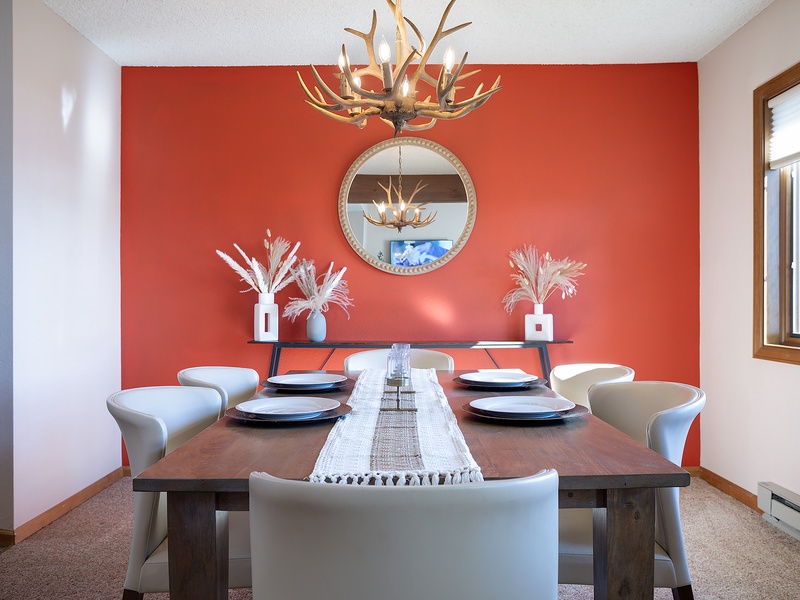 Gather around your private dining table beneath a striking antler chandelier, where vibrant coral tones and rustic elegance set the stage for memorable mountain meals together.