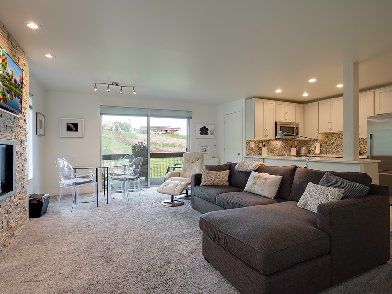 Unwind in your open-concept living space where a plush sectional invites movie nights by the fireplace, while your fully-equipped kitchen awaits your culinary adventures and vineyard views inspire relaxation.