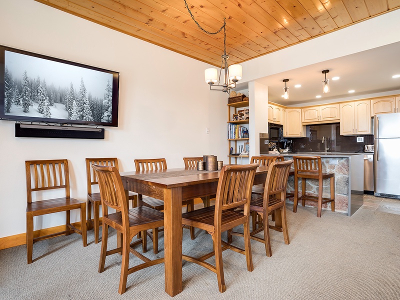 Gather around the handcrafted wooden table for meals and laughter, with a warm vaulted ceiling overhead and a fully equipped kitchen just steps away for easy entertaining.