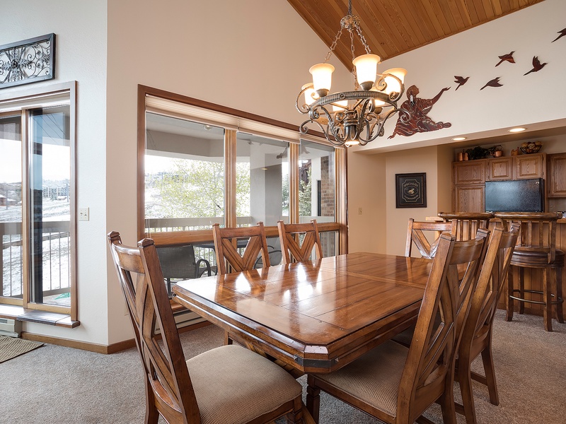 Gather around the handcrafted dining table under vaulted wood ceilings, where warm light and whimsical bird art create an inviting space for shared meals and memorable conversations.