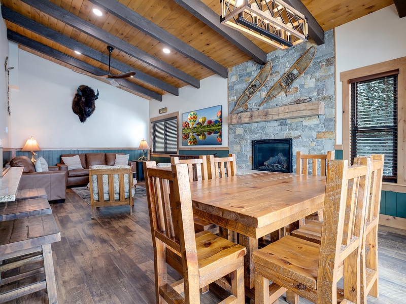 Gather around the handcrafted dining table where rustic wood beams meet modern mountain elegance. The soaring stone fireplace and cozy seating invite you to unwind after your adventures.