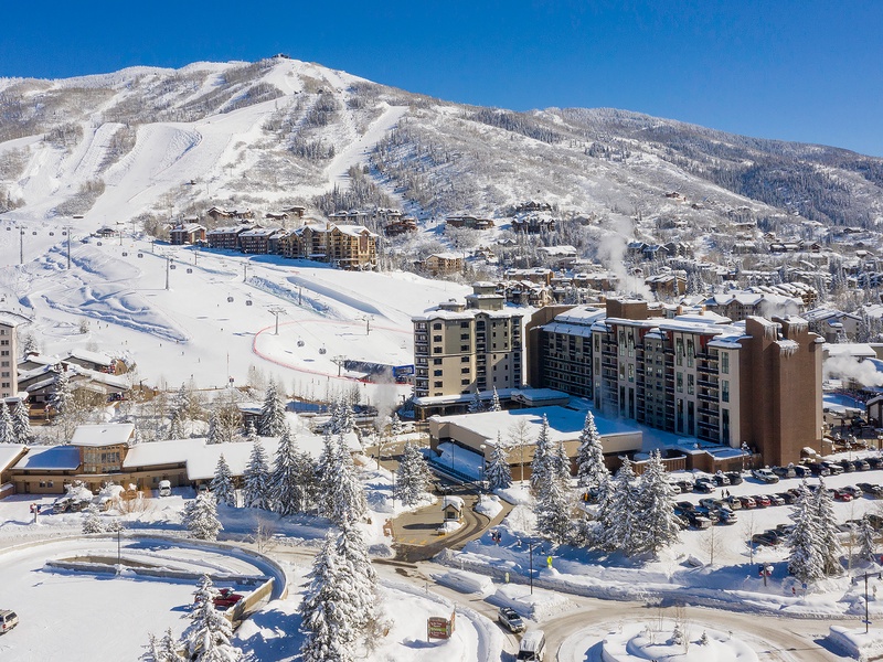 Aerial view of the property nestled at the base of pristine ski slopes, offering direct access to winter recreation and stunning mountain scenery.