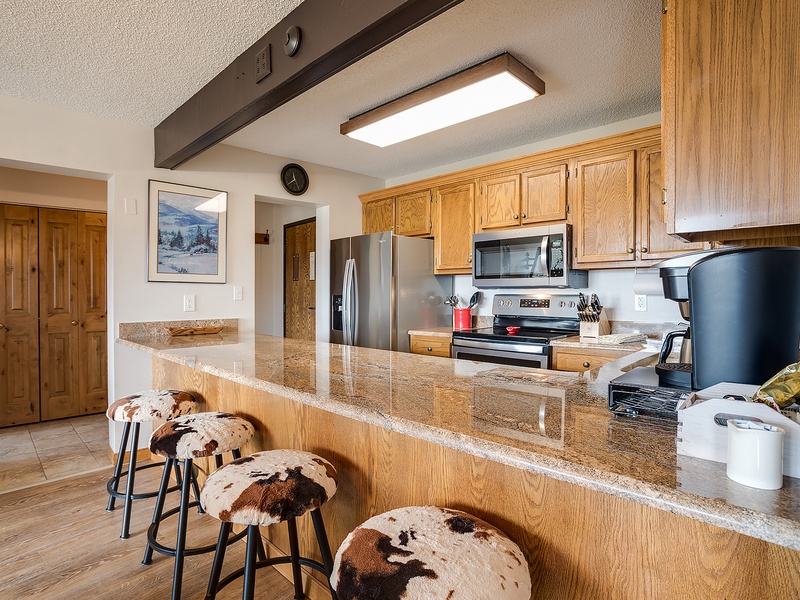 Your fully-equipped kitchen features granite countertops, stainless-steel appliances, and a breakfast bar with cowhide stools, perfect for morning coffee or casual meals.