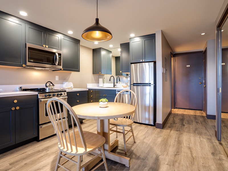 Your fully equipped kitchen features elegant dark cabinetry, stainless steel appliances, and a cozy dining nook—perfect for preparing and enjoying homemade meals during your stay.
