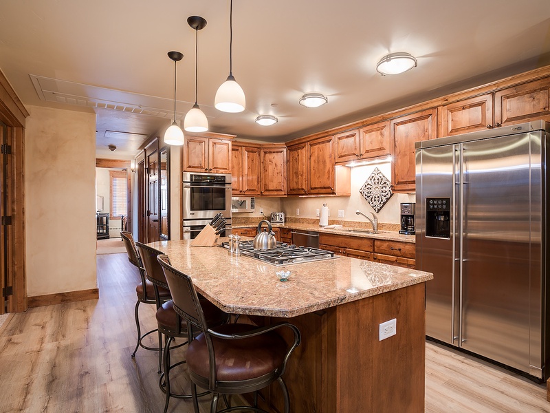Gather around this spacious gourmet kitchen where rich wood cabinetry, granite countertops, and stainless steel appliances await your culinary adventures. The center island seats four, perfect for cooking together or enjoying morning coffee.