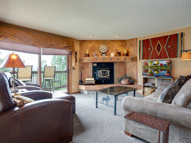 Unwind in your cozy living room, where plush seating and a warm fireplace invite you to relax after a day of adventure, with natural light and patio access.