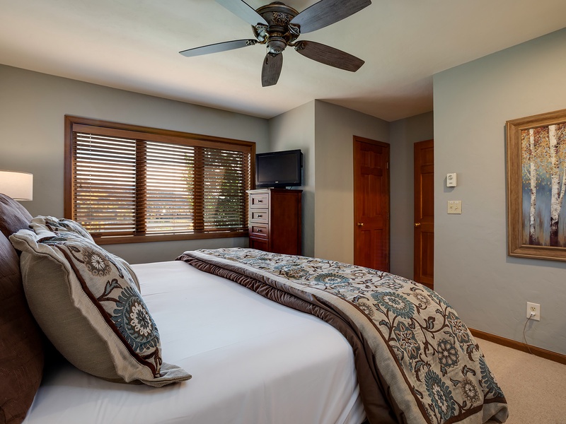 Unwind in your serene bedroom, where soft linens and gentle ceiling fan breezes promise restful nights. Natural light filters through wooden blinds, creating a peaceful retreat after your adventures.