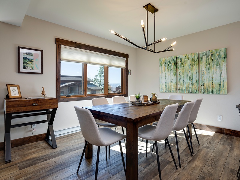Gather around this inviting dining table where shared meals become treasured memories. The modern chandelier and natural light create a warm ambiance perfect for your morning coffee or evening dinners.