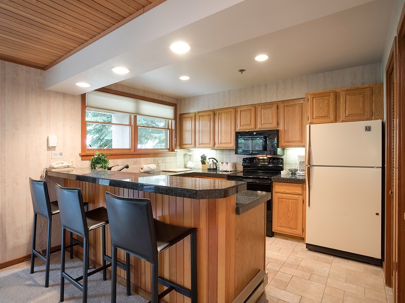 Your fully equipped kitchen features warm wood cabinetry, granite countertops, and modern appliances. Gather at the breakfast bar for morning coffee or casual meals together.