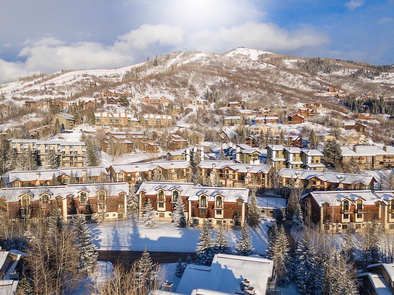 A pristine mountain resort community nestled beneath snow-dusted slopes, surrounded by evergreens and alpine peaks—perfect for winter getaways.