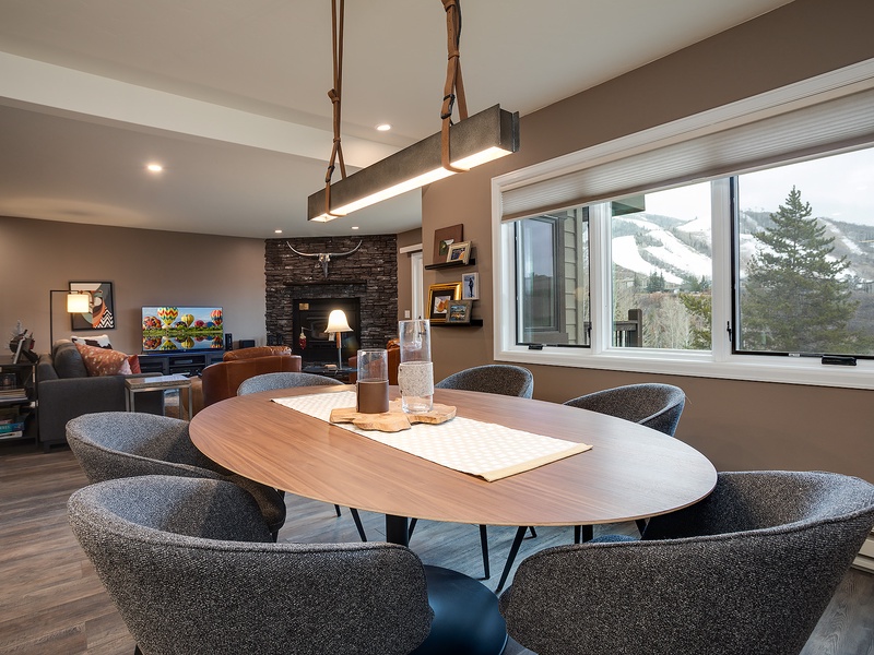 Gather around this stylish oval table with mountain views right outside your window. The open living space flows effortlessly, perfect for memorable meals and cozy evenings by the fire.