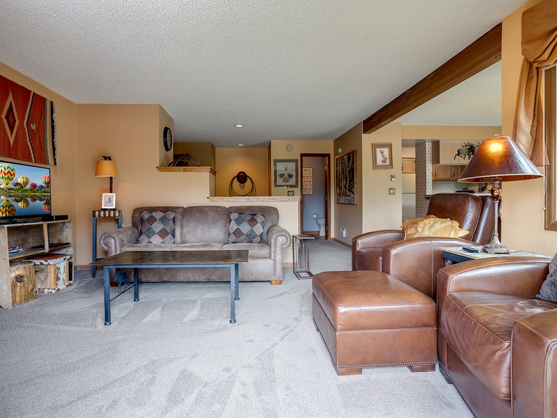 Sink into plush leather seating and unwind in your spacious living room, where warm wood accents and thoughtful decor create a cozy mountain retreat after a day of adventure.