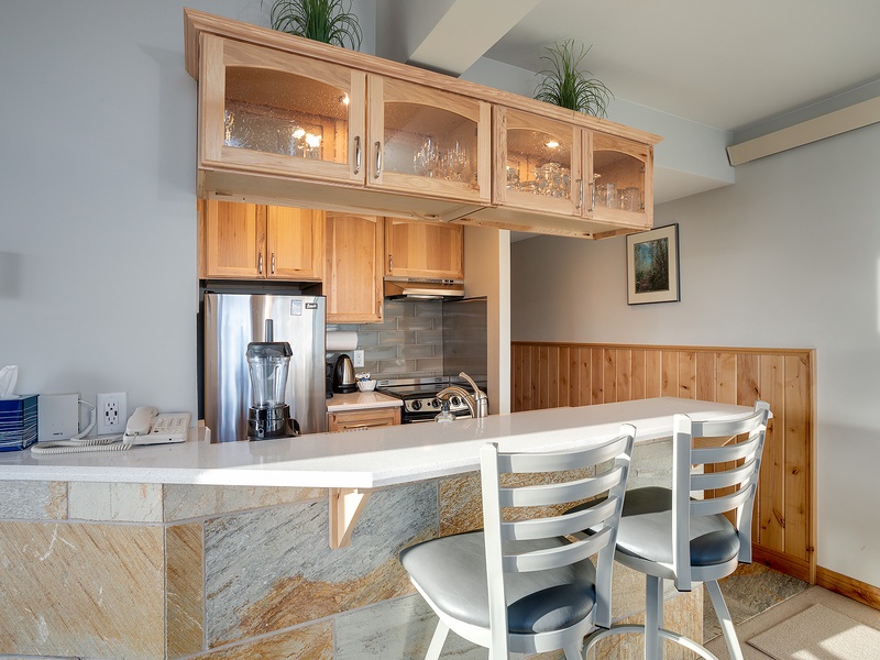 Your fully equipped kitchen features warm wood cabinetry, stainless appliances, and a convenient breakfast bar—perfect for enjoying morning coffee or preparing memorable meals together.