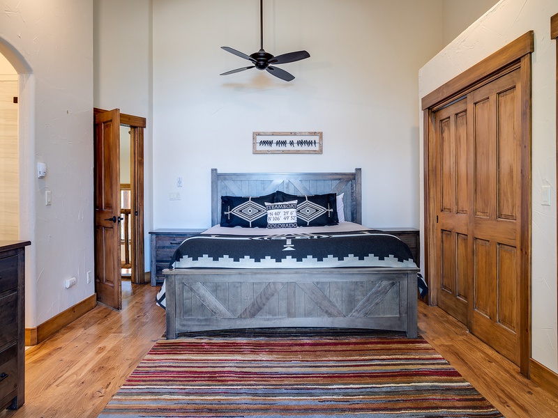 Sink into the plush bedding beneath soaring ceilings and a gentle ceiling fan. Rich wooden accents, a cozy striped rug, and thoughtful details create your perfect retreat after a day of exploring.