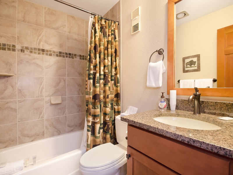 Refresh in your private bathroom with a sleek granite vanity, soaking tub with tile surround, and thoughtful touches like fresh towels and rustic wildlife accents that add a cozy charm.