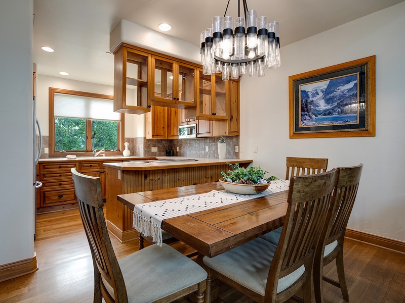 Gather around the warm wood table for meals in this inviting dining area, where rich cabinetry and a stunning chandelier create a cozy mountain retreat atmosphere.
