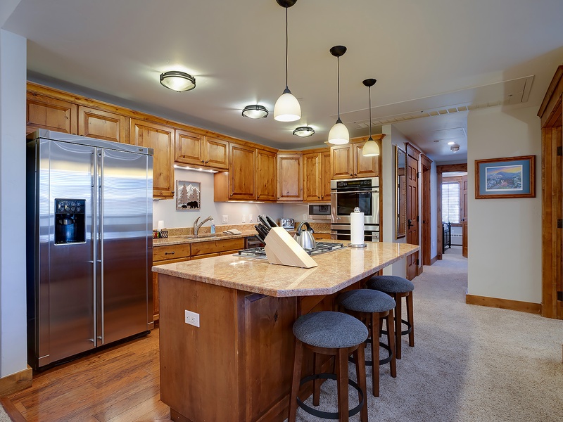 A beautifully appointed kitchen awaits your culinary adventures, featuring granite countertops, stainless steel appliances, and an island with seating for casual meals or morning coffee.