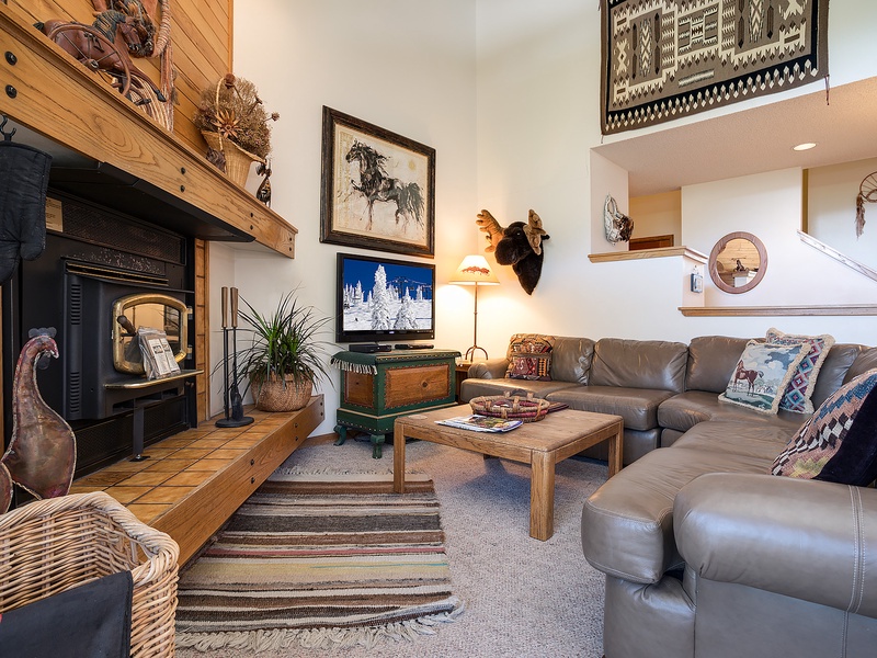 Sink into the soft leather sectional by the glowing fireplace, where rustic wood beams and mountain-inspired art welcome you to your cozy retreat.