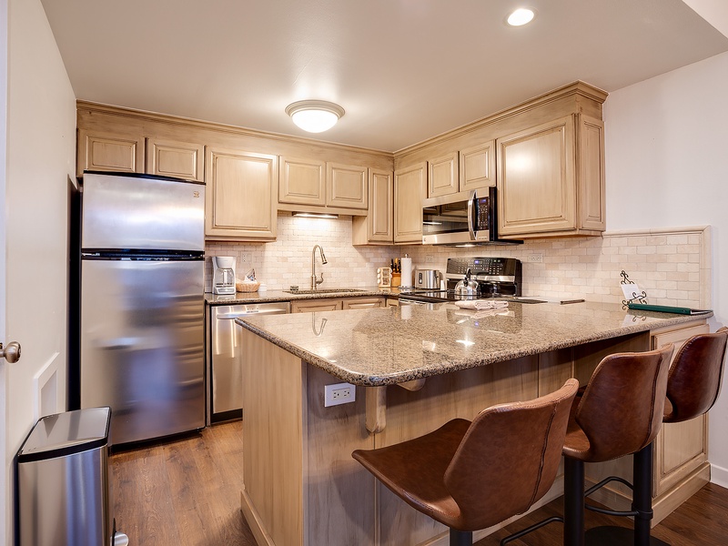 Your fully equipped kitchen with stainless steel appliances, granite countertops, and a breakfast bar awaits, perfect for preparing meals or enjoying morning coffee in style.