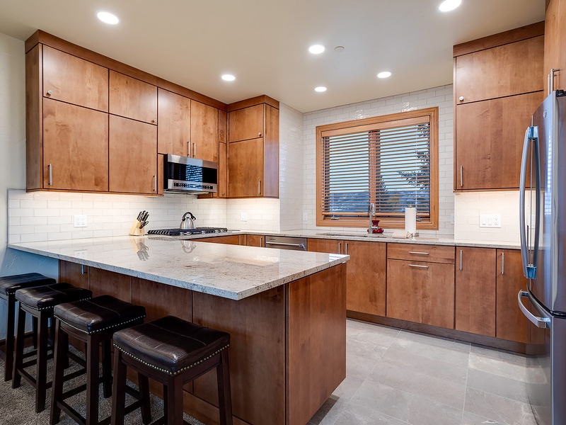 Your fully equipped kitchen features sleek granite countertops, stainless steel appliances, and a spacious island with seating—perfect for cooking and gathering together.