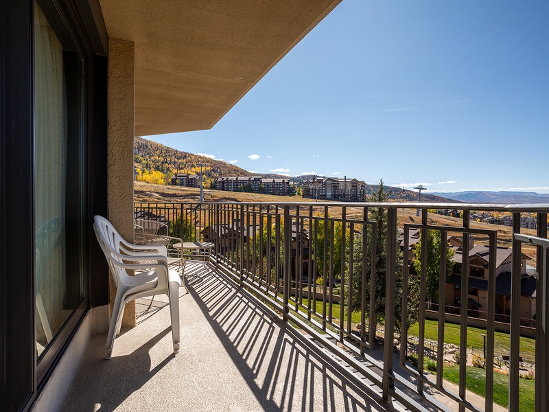 Balcony overlooking mountains and seasonal foliage, with nearby resort buildings in view. Outdoor seating included for enjoying the surrounding landscape.