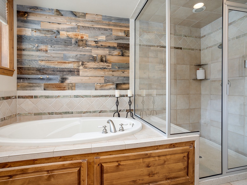 Unwind in your private spa-like bathroom with a soaking tub for relaxation and a walk-in shower framed by elegant tile and rustic wood accents.