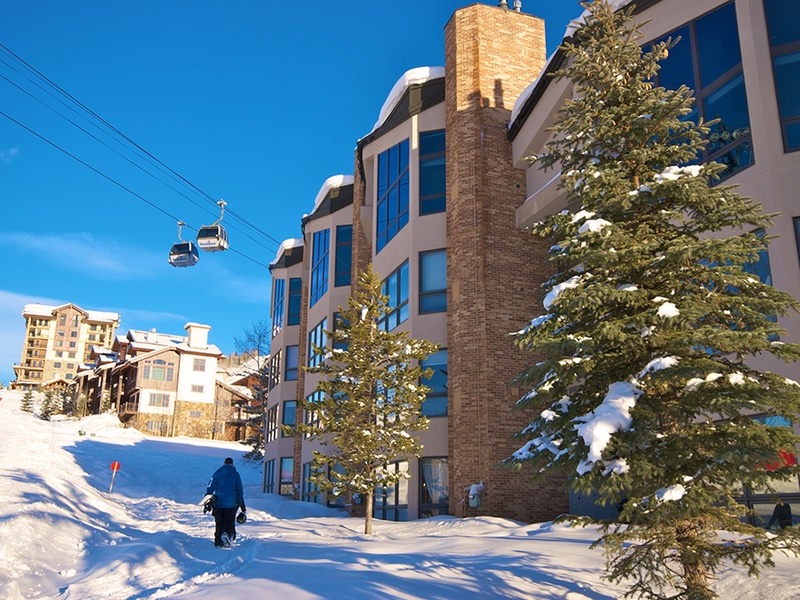 Ski-in, ski-out property nestled on the snowy slopes with mountain gondola access, offering direct access to winter adventures beneath brilliant blue skies.