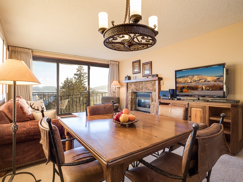 Settle into your cozy retreat with stunning mountain views through expansive balcony doors. Gather around the dining table, warm up by the fireplace, and enjoy home entertainment in this inviting space.