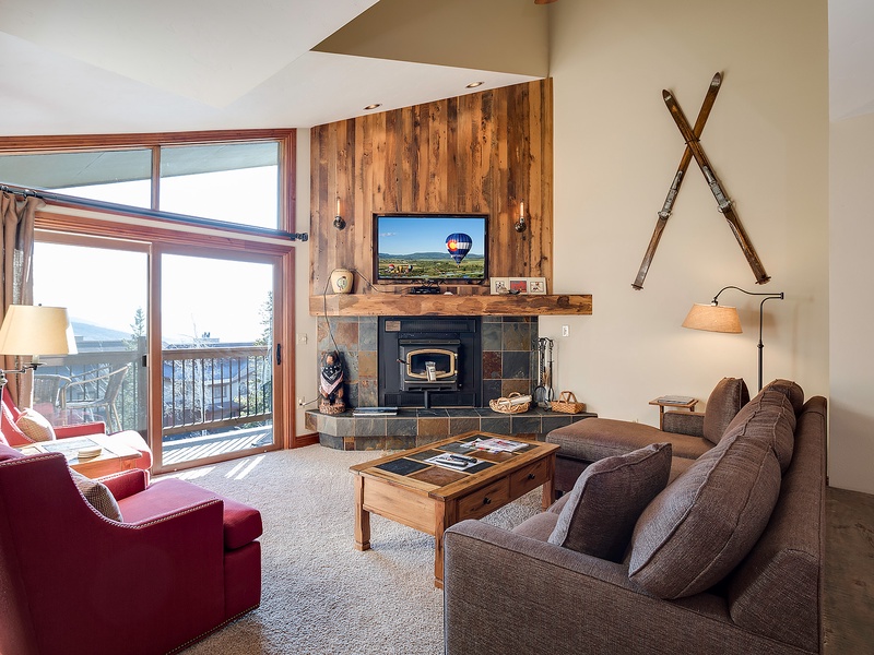 Picture yourself unwinding in this bright, spacious living room with soaring ceilings, cozy fireplace, and stunning mountain views through floor-to-ceiling windows—your perfect retreat after a day of adventure.