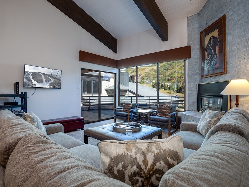 Sink into plush seating as natural light pours through floor-to-ceiling windows. Your private retreat features exposed beams, a cozy fireplace, and mountain views from your balcony.