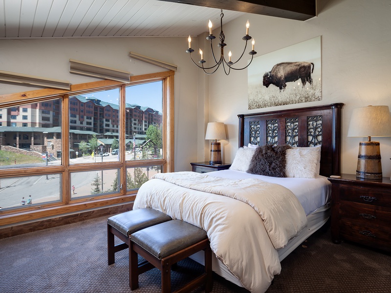 Sink into plush bedding beneath a rustic chandelier, with textured pillows and mountain-inspired décor inviting you to unwind in style.