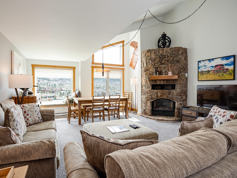 Unwind in this bright, spacious living room with cozy seating, a stone fireplace, and stunning mountain views—your perfect alpine retreat awaits.