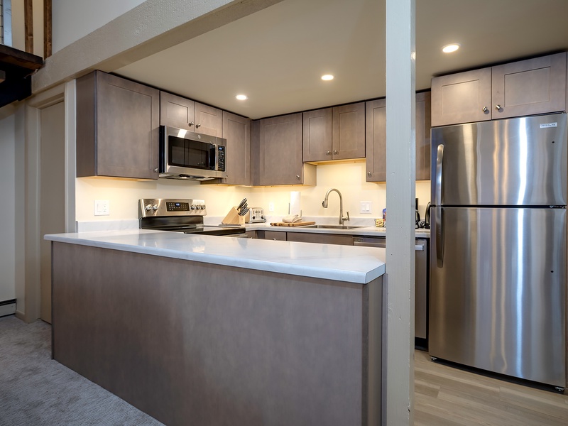 Your modern kitchen features stainless steel appliances, sleek countertops, and warm ambient lighting—perfect for preparing home-cooked meals during your stay.