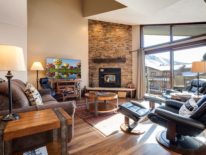 Unwind in your inviting living room with soaring ceilings, a cozy stone fireplace, and sweeping mountain views through expansive windows. Your perfect retreat after a day of adventure.