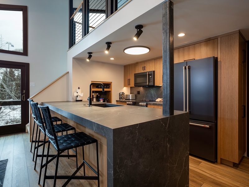 Your gourmet kitchen invites you to create culinary masterpieces at this sleek island, while natural light pours in through expansive windows framing serene winter views.