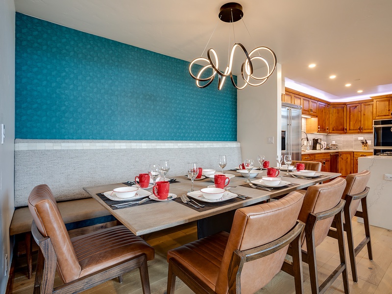 Gather around your private dining table, where a striking teal accent wall and modern chandelier create the perfect setting for memorable meals with loved ones.