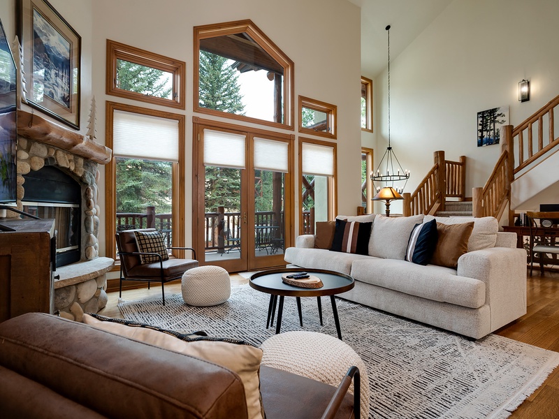 Unwind in your bright and spacious living room, where soaring ceilings and floor-to-ceiling windows frame serene forest views. Sink into plush seating by the stone fireplace and let natural light fill your mountain retreat.