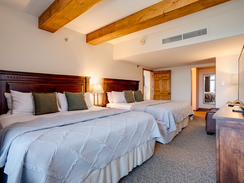 Sink into crisp linens and unwind beneath rustic beams. Two plush beds invite restful nights, while natural wood details and modern comfort create your perfect mountain retreat.