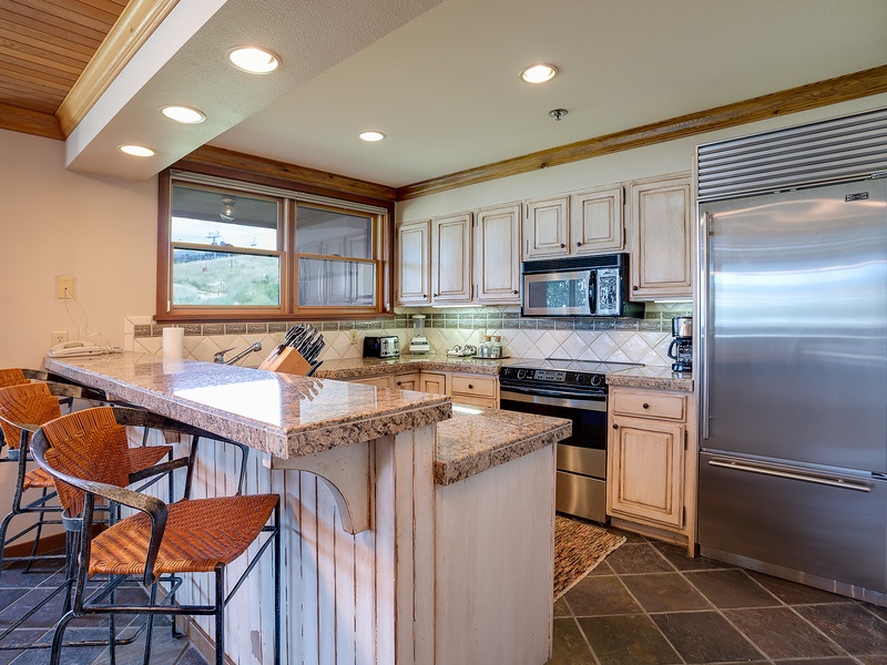 Your fully equipped kitchen features granite countertops, stainless steel appliances, and an inviting breakfast bar perfect for casual meals and morning coffee.